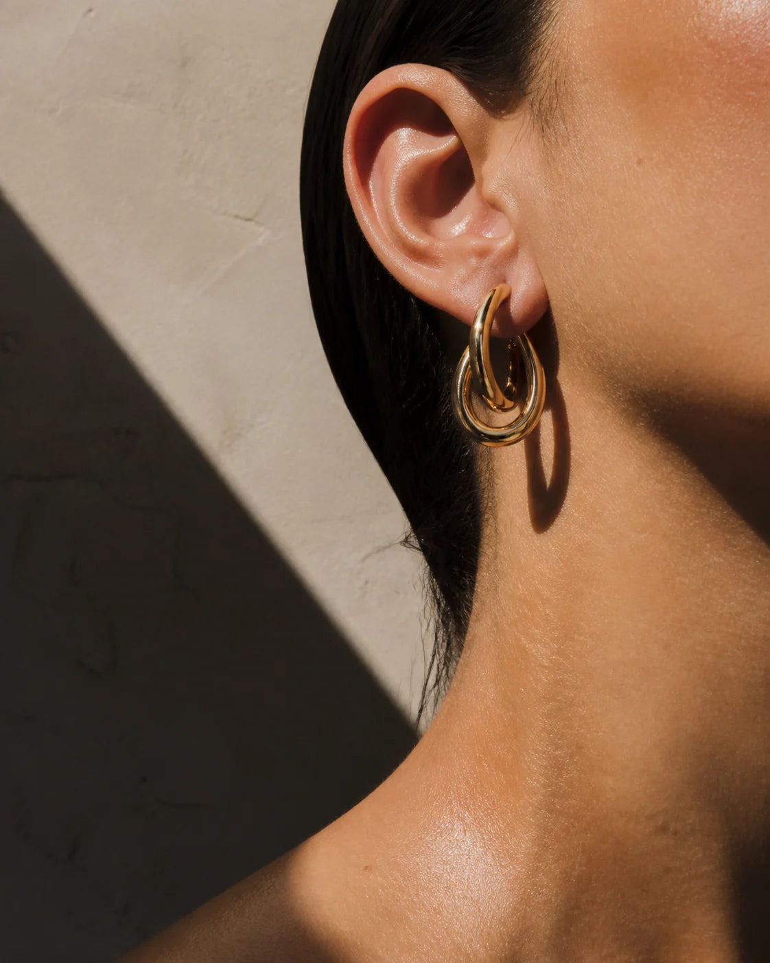 Sculptural gold hoop earring concept worn on ear